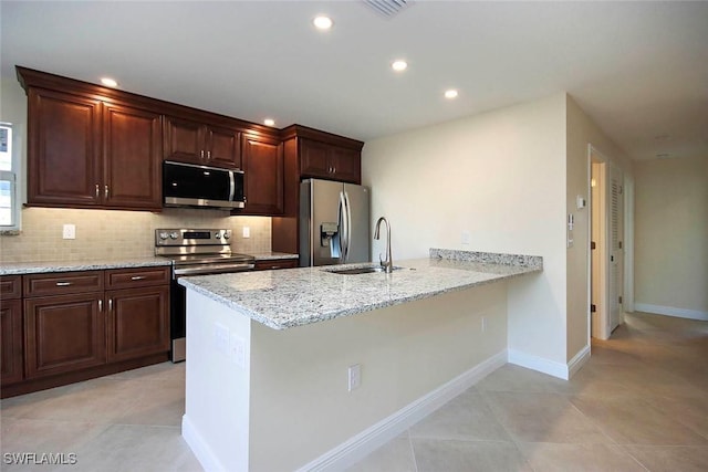 kitchen with light stone countertops, light tile patterned floors, appliances with stainless steel finishes, and sink