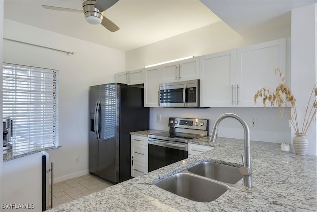 kitchen with stainless steel appliances, sink, white cabinets, and light stone counters