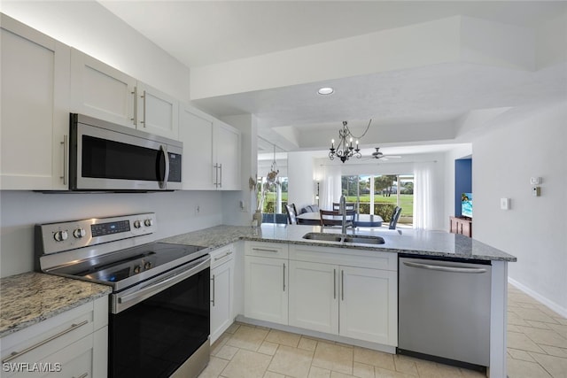 kitchen featuring sink, white cabinetry, stainless steel appliances, light stone counters, and kitchen peninsula