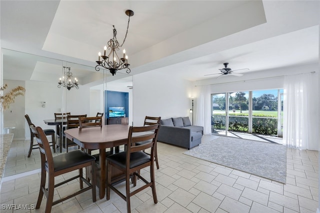 dining room featuring a tray ceiling and ceiling fan with notable chandelier