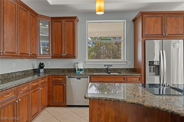 kitchen featuring light tile patterned flooring, sink, appliances with stainless steel finishes, and dark stone countertops