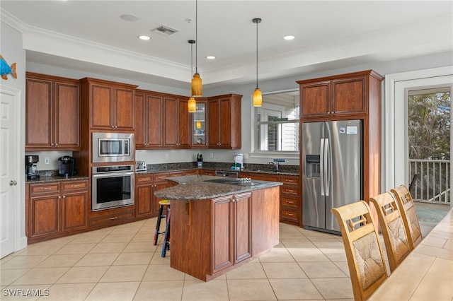 kitchen with decorative light fixtures, appliances with stainless steel finishes, a center island, and ornamental molding