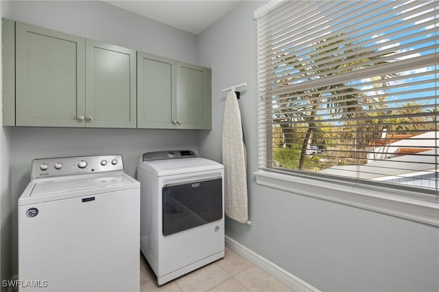 laundry room featuring cabinets, light tile patterned floors, and washing machine and clothes dryer