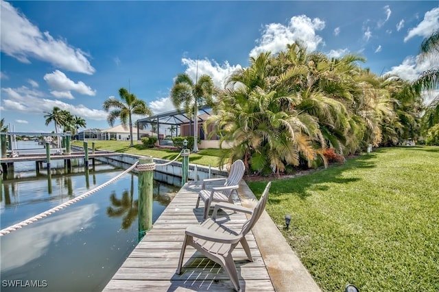 view of dock with glass enclosure, a water view, and a lawn