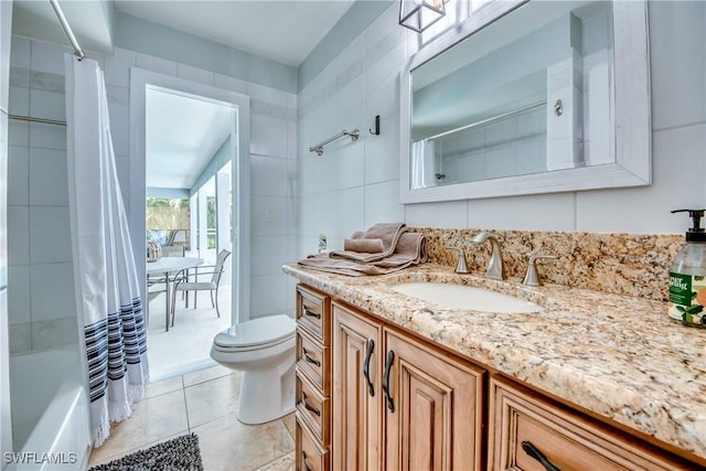 full bathroom featuring toilet, tile walls, shower / bath combination with curtain, tile patterned floors, and vanity