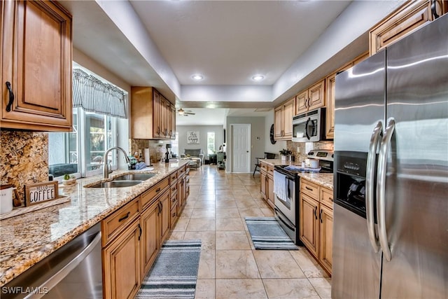 kitchen featuring sink, light tile patterned floors, light stone countertops, decorative backsplash, and stainless steel appliances