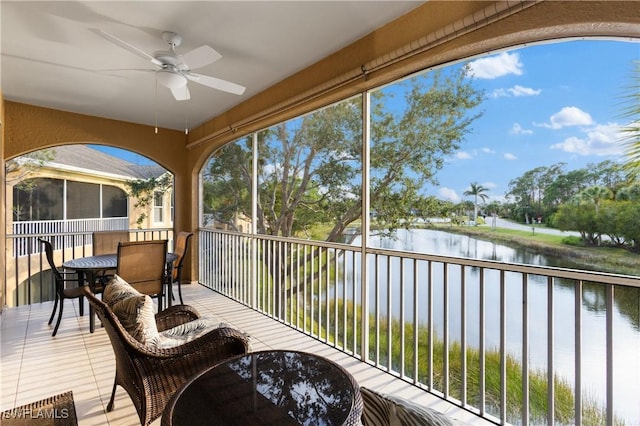 sunroom / solarium featuring a water view and ceiling fan