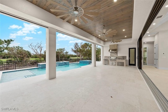 view of pool with a patio area, ceiling fan, an outdoor kitchen, and pool water feature