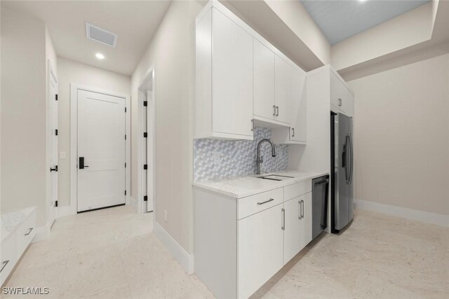 kitchen featuring sink, white cabinetry, appliances with stainless steel finishes, and decorative backsplash