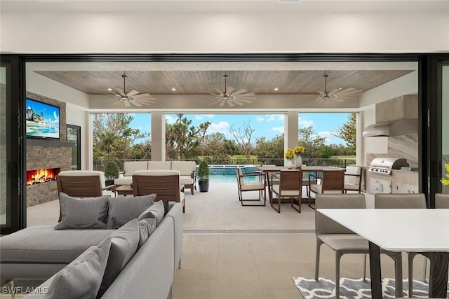 view of patio / terrace with area for grilling, an outdoor living space with a fireplace, and ceiling fan