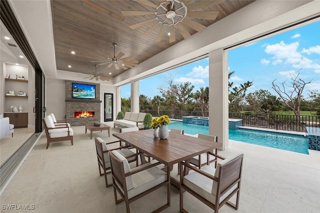 view of patio featuring a fireplace, a fenced in pool, pool water feature, and ceiling fan