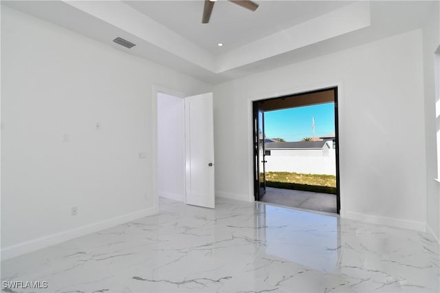 foyer with ceiling fan and a raised ceiling