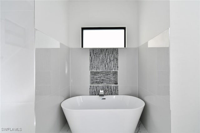 bathroom featuring tile walls and a washtub