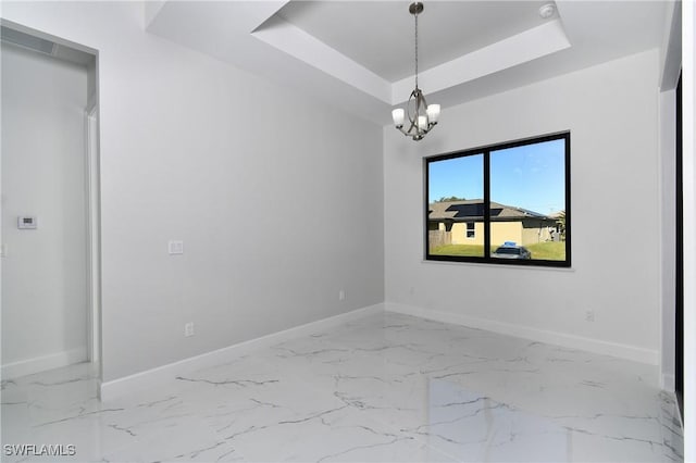 empty room with a raised ceiling and a notable chandelier