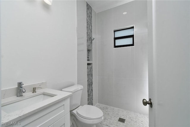 bathroom with toilet, vanity, and a tile shower