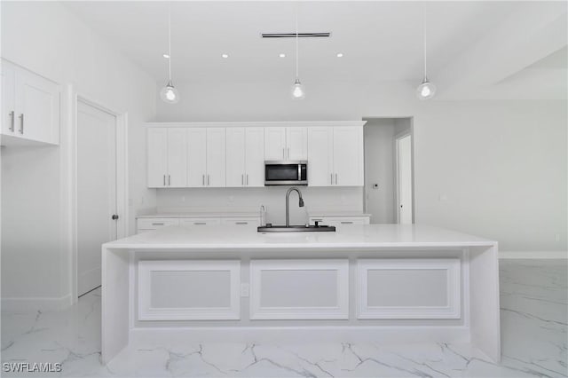 kitchen featuring white cabinetry, pendant lighting, and a kitchen island with sink