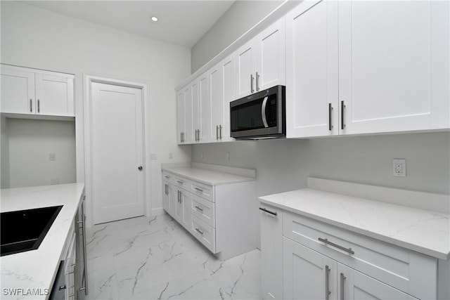 kitchen featuring light stone counters, sink, and white cabinets