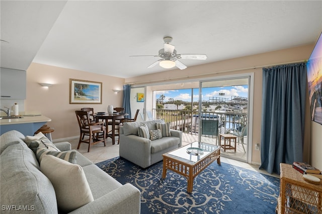 tiled living room with ceiling fan, sink, and a water view