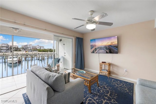 tiled living room with ceiling fan and a water view