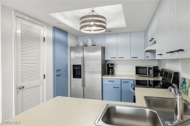 kitchen featuring sink, decorative light fixtures, a tray ceiling, and appliances with stainless steel finishes