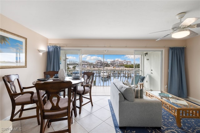 dining space with ceiling fan, a water view, and light tile patterned flooring