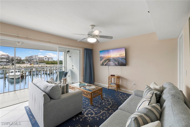 living room featuring a water view, light tile patterned floors, and ceiling fan