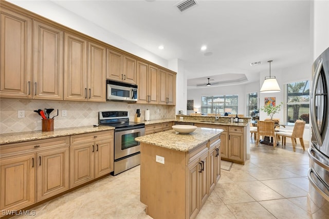 kitchen featuring a kitchen island, kitchen peninsula, hanging light fixtures, stainless steel appliances, and light stone counters