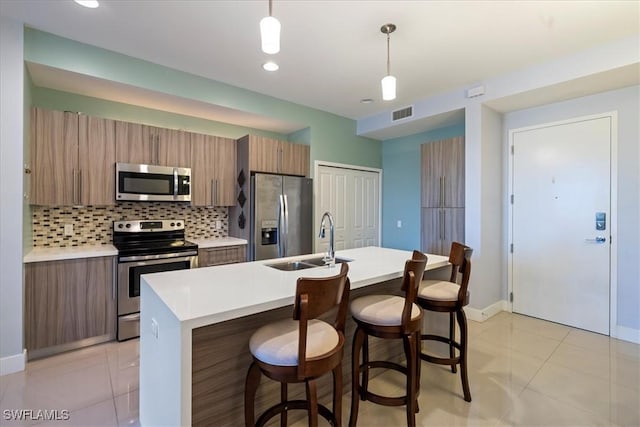 kitchen with light tile patterned floors, stainless steel appliances, backsplash, pendant lighting, and sink