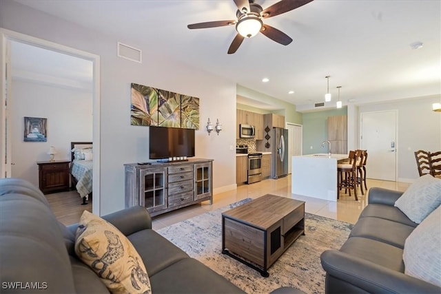 tiled living room featuring ceiling fan and sink