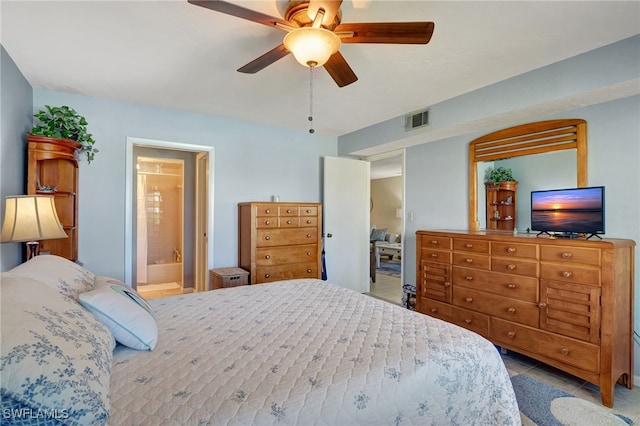 bedroom with ensuite bathroom, light tile patterned flooring, and ceiling fan