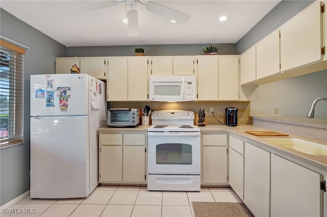 kitchen featuring light tile patterned flooring, cream cabinets, sink, and white appliances