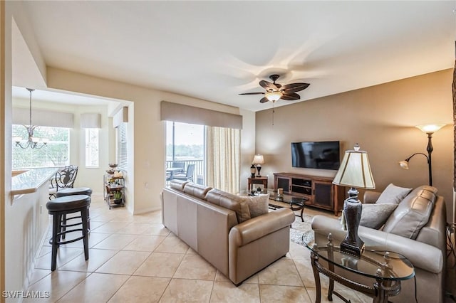 tiled living room with ceiling fan with notable chandelier