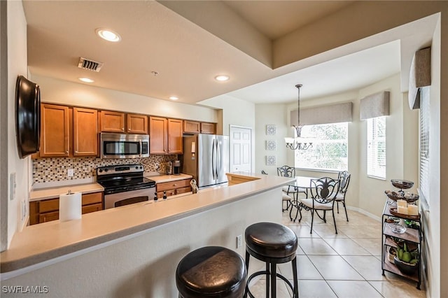 kitchen featuring stainless steel appliances, tasteful backsplash, hanging light fixtures, a breakfast bar, and light tile patterned floors