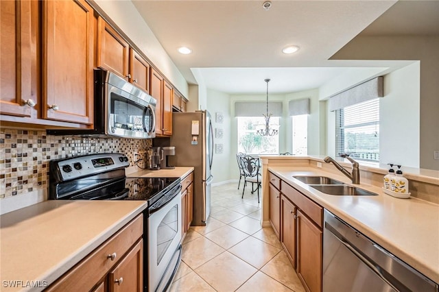 kitchen featuring a wealth of natural light, appliances with stainless steel finishes, tasteful backsplash, hanging light fixtures, and sink