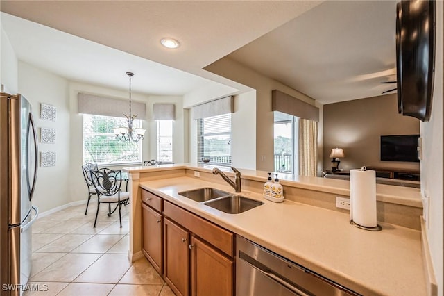 kitchen featuring appliances with stainless steel finishes, sink, hanging light fixtures, a notable chandelier, and light tile patterned floors