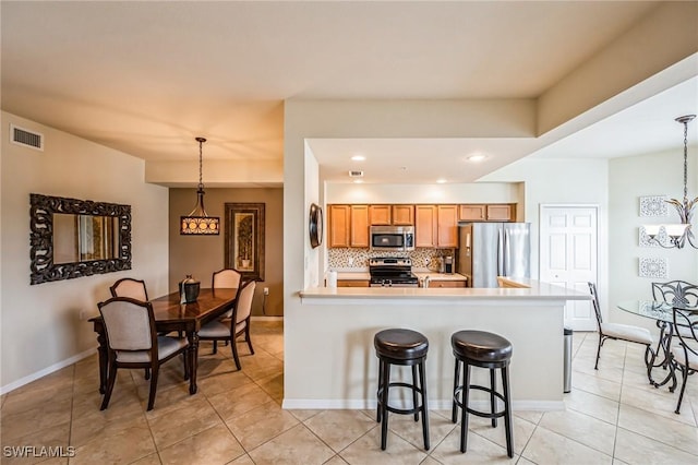 kitchen featuring a notable chandelier, appliances with stainless steel finishes, tasteful backsplash, decorative light fixtures, and light tile patterned flooring