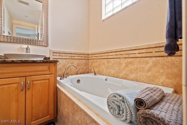 bathroom with tiled tub and vanity