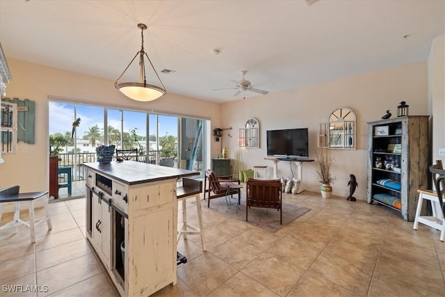 kitchen featuring light tile patterned floors, a kitchen island, ceiling fan, and decorative light fixtures