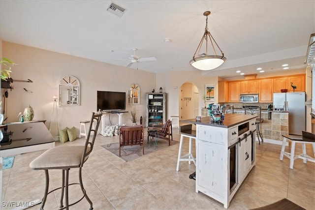 kitchen featuring light tile patterned floors, hanging light fixtures, appliances with stainless steel finishes, and a kitchen island