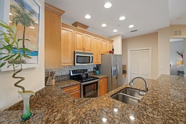 kitchen featuring decorative backsplash, sink, stainless steel appliances, and dark stone countertops