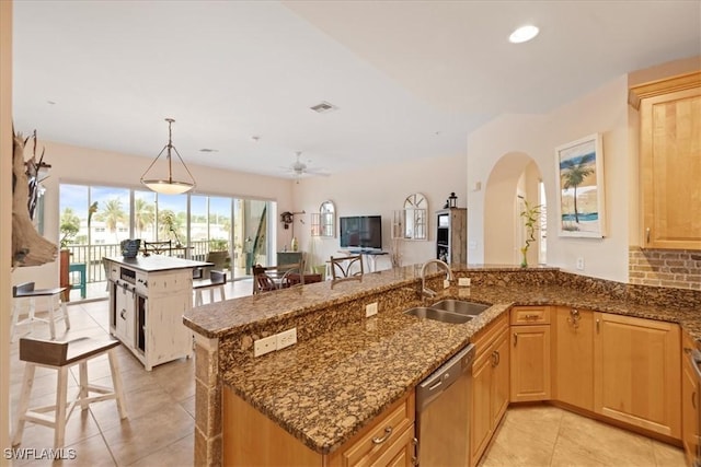 kitchen with dishwasher, dark stone countertops, sink, hanging light fixtures, and light tile patterned floors