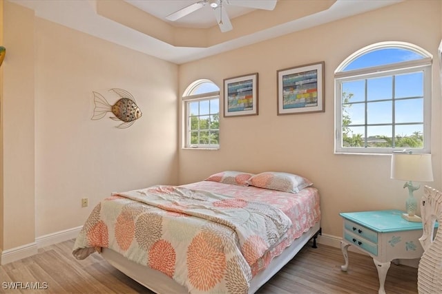 bedroom featuring ceiling fan, a tray ceiling, and hardwood / wood-style floors