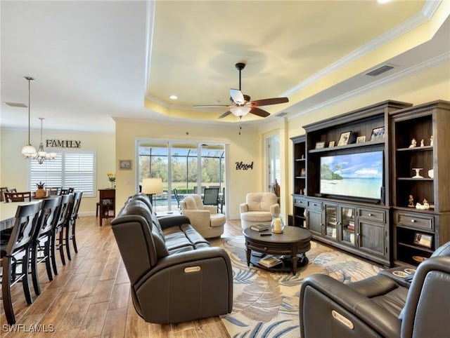 living room with ceiling fan with notable chandelier, crown molding, and a raised ceiling