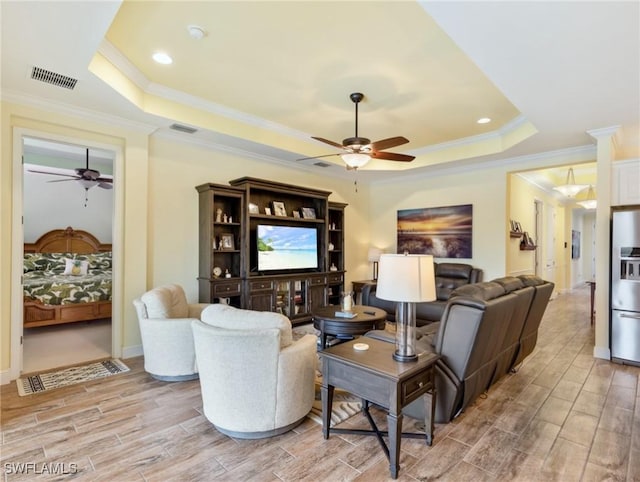 living room featuring ceiling fan, a tray ceiling, and ornamental molding