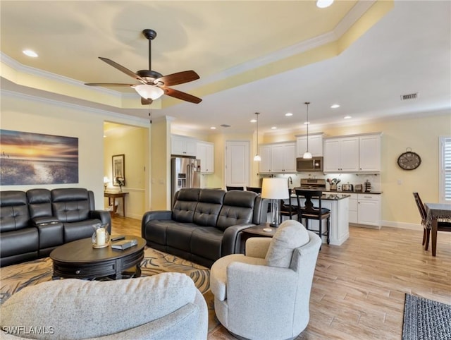 living room featuring crown molding, ceiling fan, and a raised ceiling