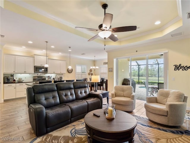 living room with ceiling fan, ornamental molding, and a tray ceiling