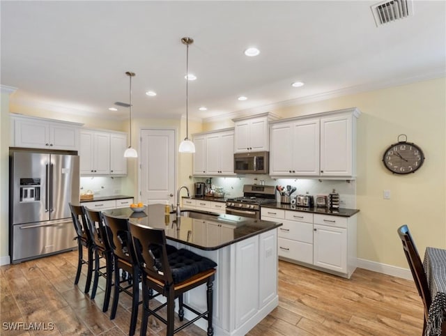 kitchen with sink, a breakfast bar area, white cabinetry, and appliances with stainless steel finishes