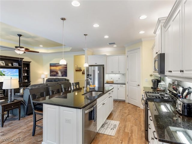 kitchen featuring white cabinets, stainless steel appliances, and an island with sink