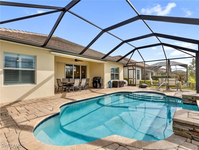 view of swimming pool featuring glass enclosure, ceiling fan, and a patio