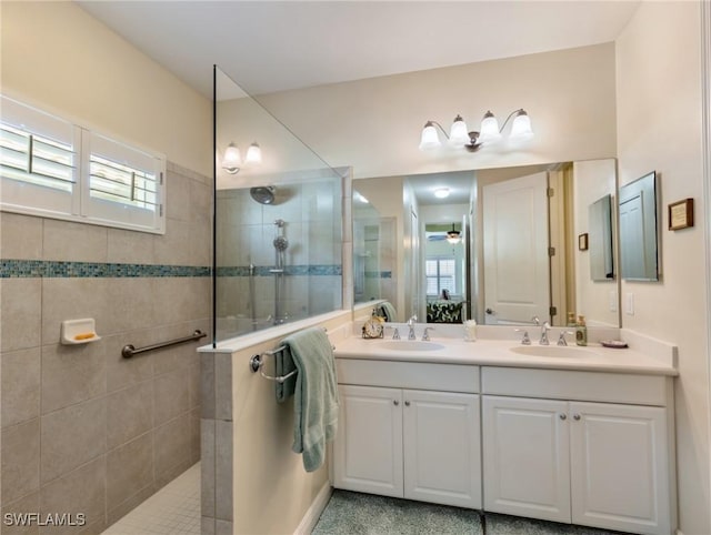 bathroom with vanity, ceiling fan, and a tile shower